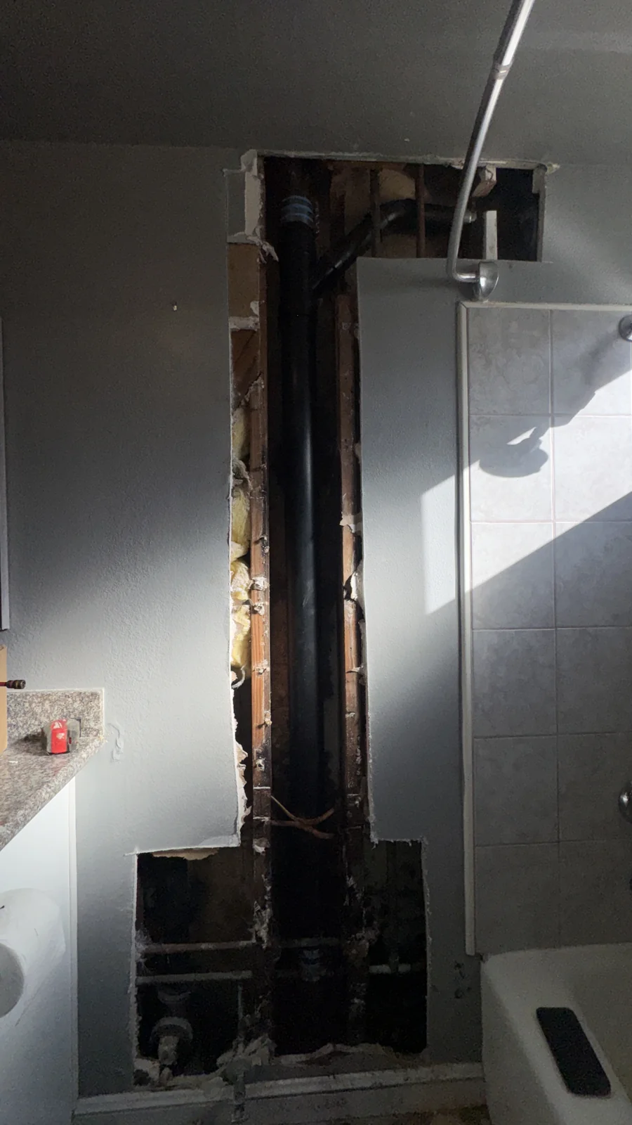 Plumbing exposed beside a shower enclosure